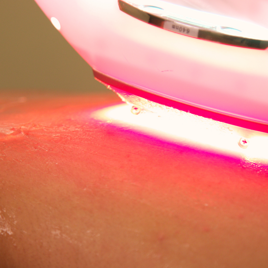 Cold laser therapy device glowing red against the skin